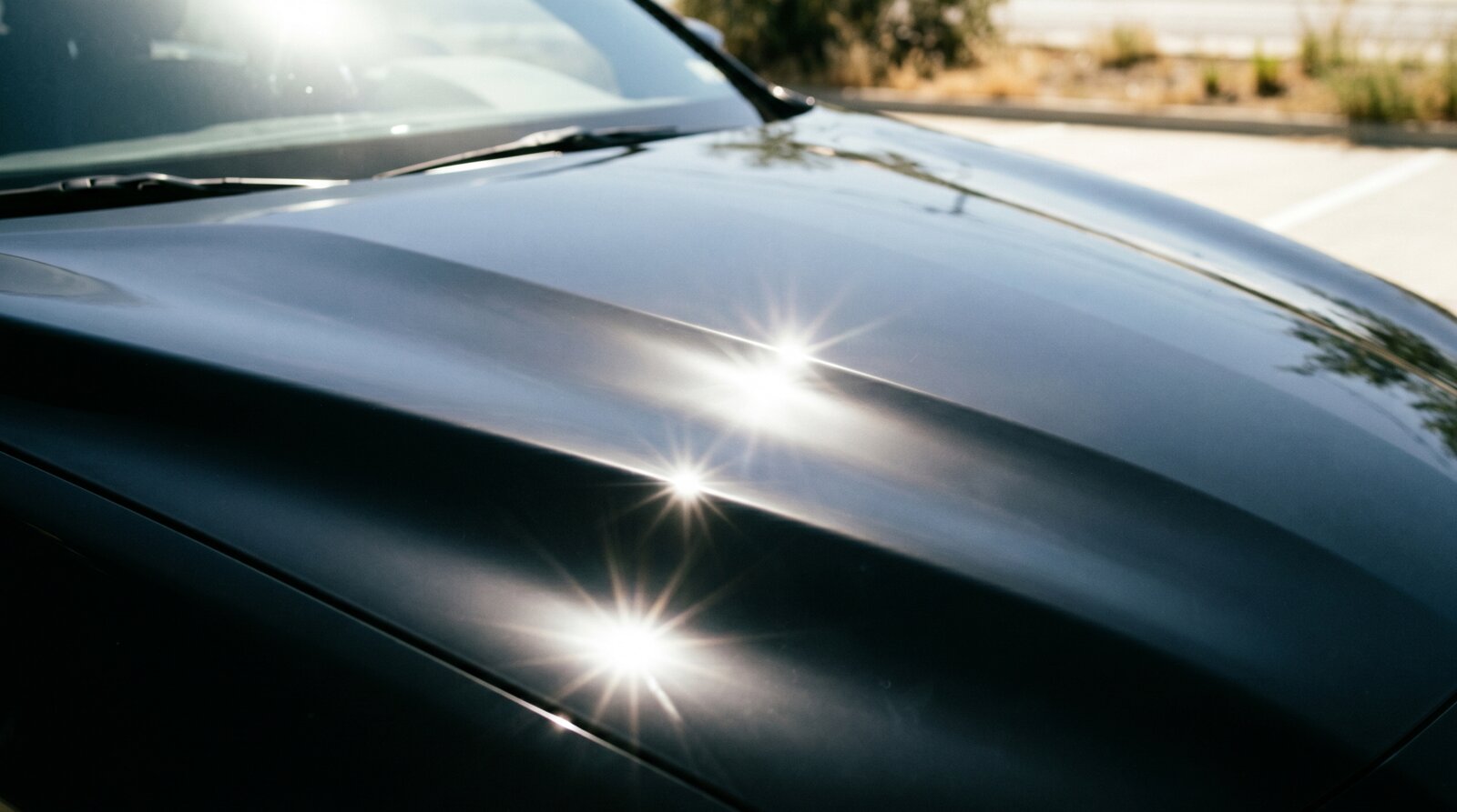 Clean black hood under harsh midday summer sun, bleached sun-star highlights and hard shadows