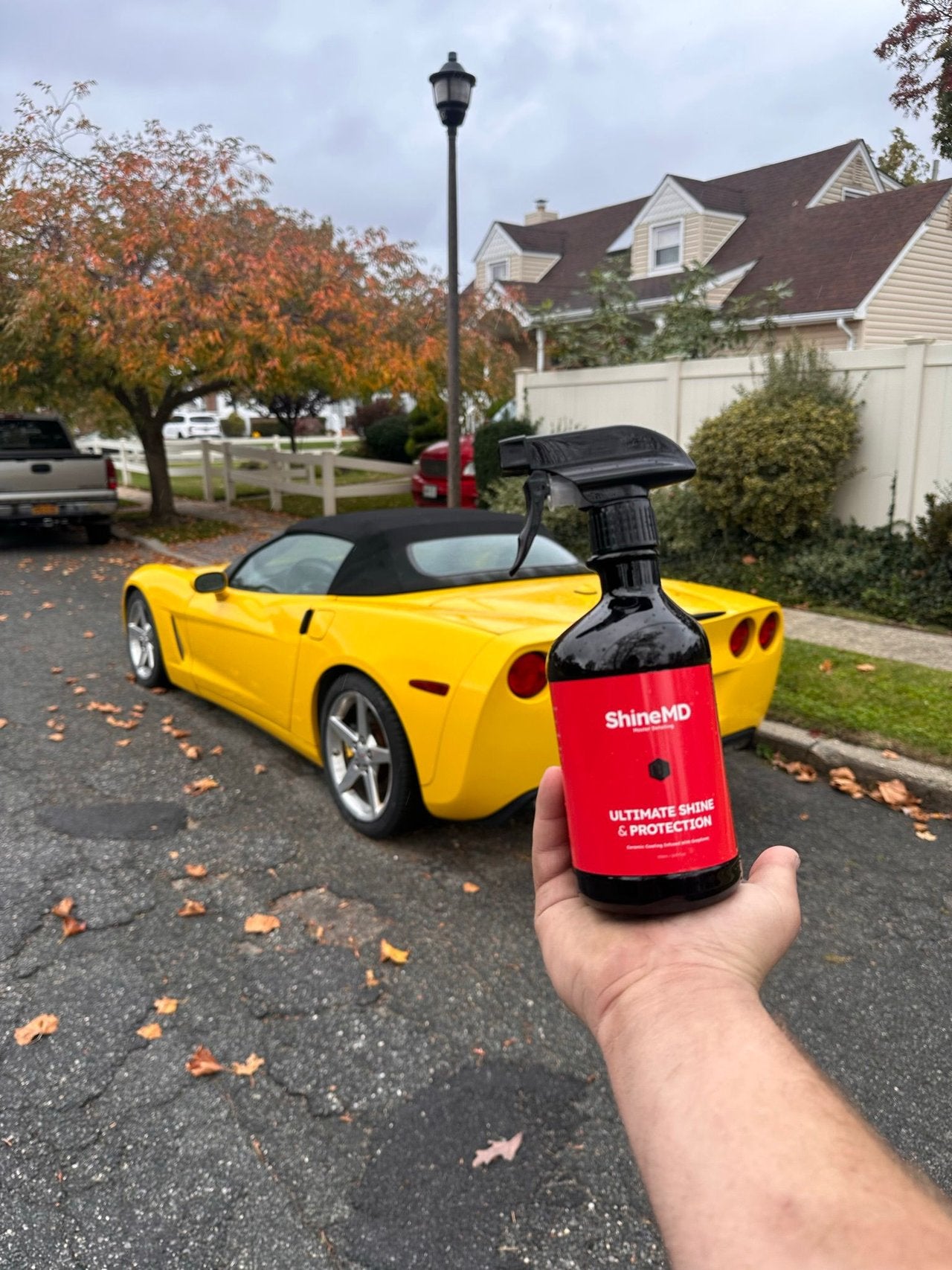 ShineMD bottle in hand in a driveway, yellow Corvette convertible behind it — the whole job is one walk-around the car